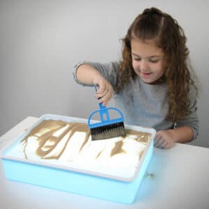 A girl playing with a portable light-up sand table.
