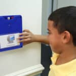 A boy moving a blue wall communicator to the word computer.